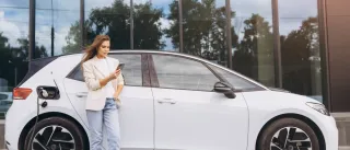 vtt-electric-car-charging.jpg a woman charging an electric car while on her mobile phone